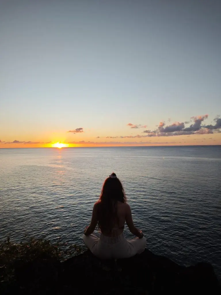 Apolline en méditation au coucher du soleil sur l'océan en Guadeloupe — moment de reconnexion à soi